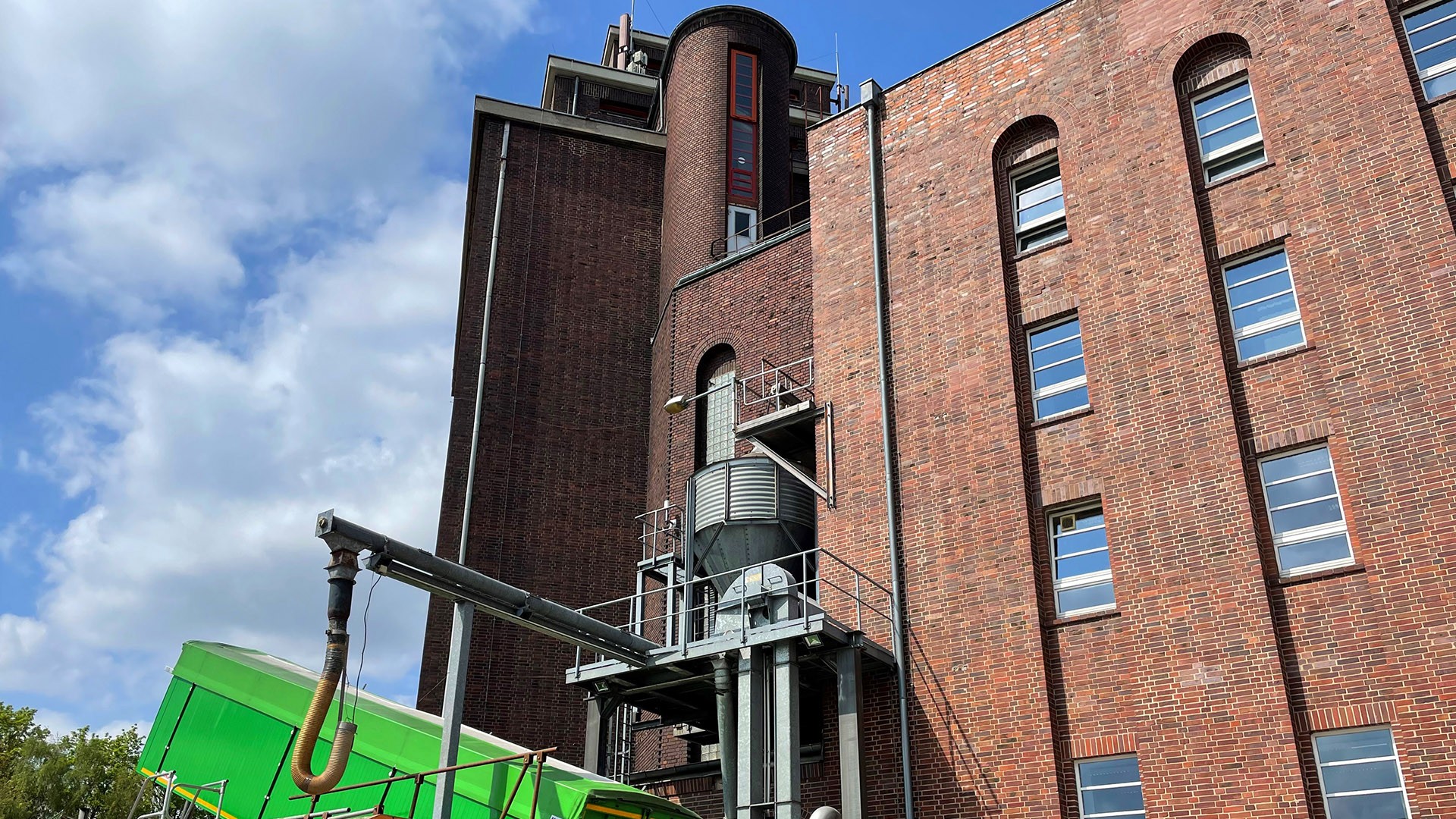 Ein industrielles Backsteingebäude unter blauem Himmel mit einem zylindrischen Turm.