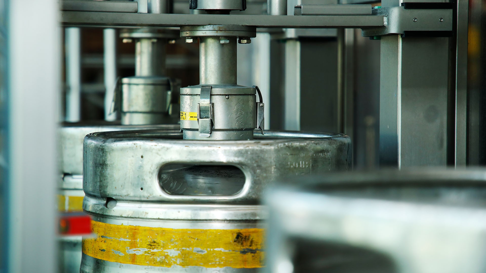 Mehrere Metallfässer sind in einer industriellen Abfüllanlage positioniert.