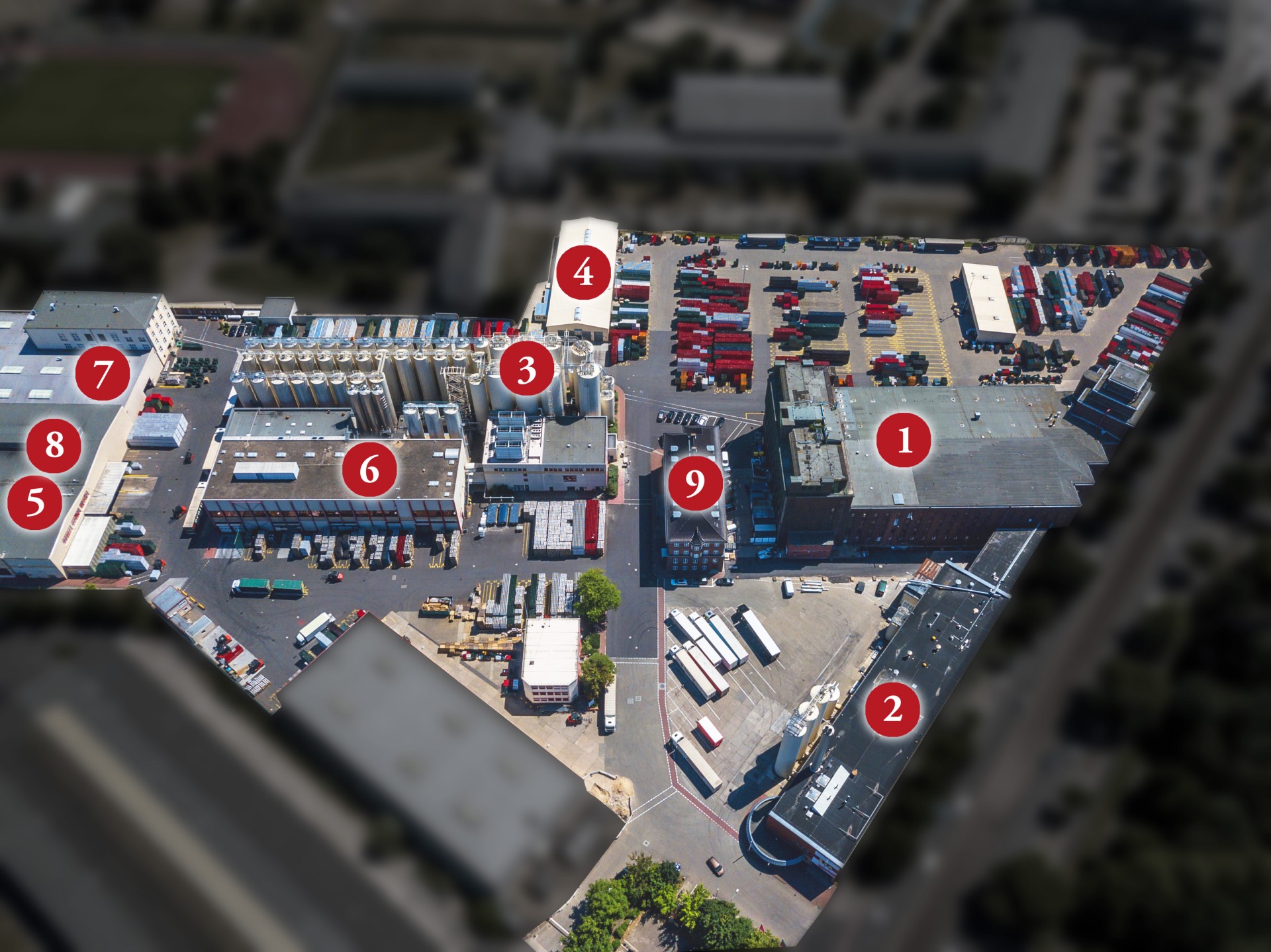 Luftbild eines Industriekomplexes mit mehreren Gebäuden und parkenden LKWs.