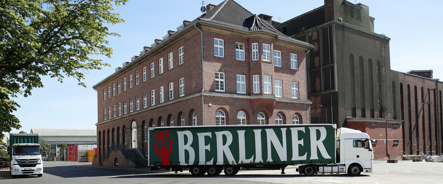 Ein Lastwagen fährt vor einem großen Backsteingebäude entlang.